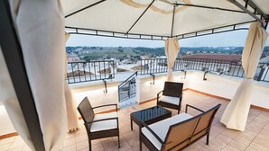 A covered outdoor seating area with wicker furniture and a view of the cityscape.