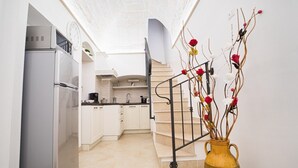 A modern kitchen with white cabinets, a stainless steel refrigerator, and a vase with flowers on the floor.
