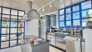 Une cuisine moderne dotée d’appareils électroménagers en acier inoxydable, d’une grande fenêtre et offrant une vue sur l’extérieur.