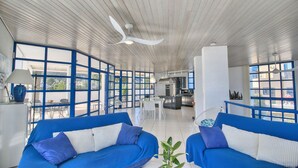 Une pièce spacieuse avec un plafond haut, de grandes fenêtres et un coin cuisine.