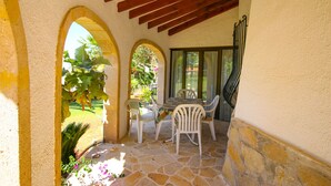 A patio with stone flooring, white chairs, and a table.
