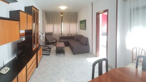 A compact living space with a sofa, chairs, a small table, and a TV. - GEMELOS 12(2 BEDROOMS) (Benidorm)