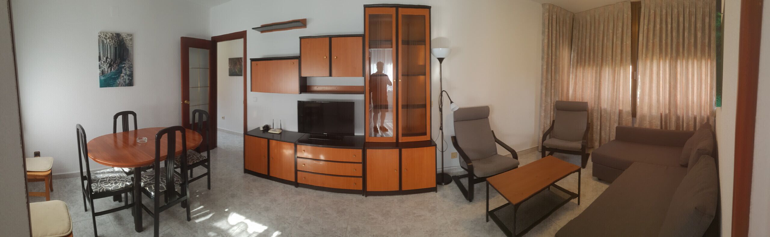A living room with a TV, a dining table with chairs, a sofa, and a cabinet.