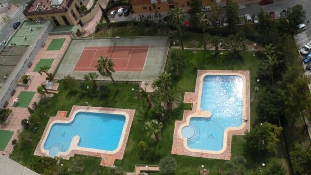 An aerial view of a residential area with two swimming pools, tennis courts, and surrounding greenery. - GEMELOS 12(2 BEDROOMS) (Benidorm)