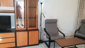 A living room with a TV, wooden cabinet, two grey armchairs, and a small table. - GEMELOS 12(2 BEDROOMS) (Benidorm)
