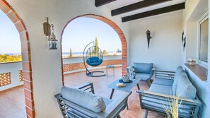 A balcony with a hanging chair, a sofa, and a table with drinks. - Villa Marquesa JM 6P with Pool and Panoramic Views in Dénia (Denia)
