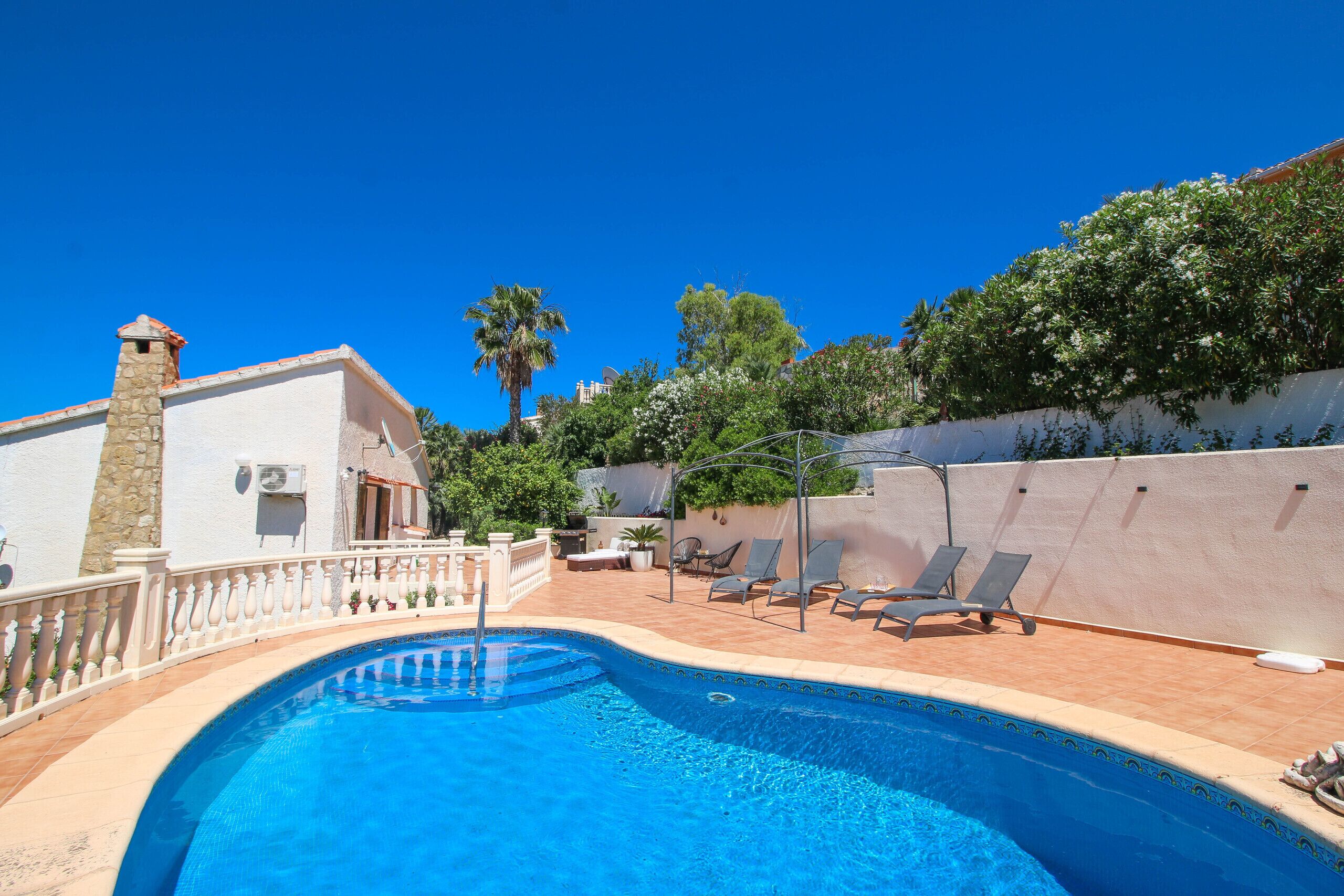 A swimming pool with lounge chairs and a stone chimney.