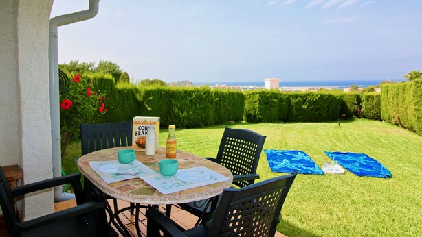 En terrasse med et bord til to, en stol og havudsigt.
