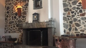 Ein Kamin aus Stein mit einer darüber befindlichen Uhr, eine Steinsäule und ein kleines Fenster.