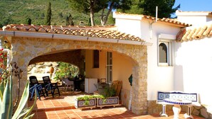Un arc en pierre mène à un patio aménagé avec des meubles d’extérieur et des plantes en pot.