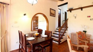 Un coin repas avec une table et des chaises en bois, un escalier et une bibliothèque.
