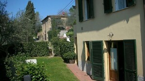 A building with green shutters, a garden with a pathway, and a distant view of a tower. - RONDINE: Peaceful farmhouse close to Tuscany 's treasures, 1mile from shops far (Poggibonsi)