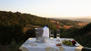 A table set with a bottle of wine, two glasses, a plate of grapes, and a candle, overlooking a scenic landscape. - RONDINE: Peaceful farmhouse close to Tuscany 's treasures, 1mile from shops far (Poggibonsi)