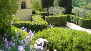 A garden with neatly trimmed hedges, a pathway, and a building with a chimney. - RONDINE: Peaceful farmhouse close to Tuscany 's treasures, 1mile from shops far (Poggibonsi)