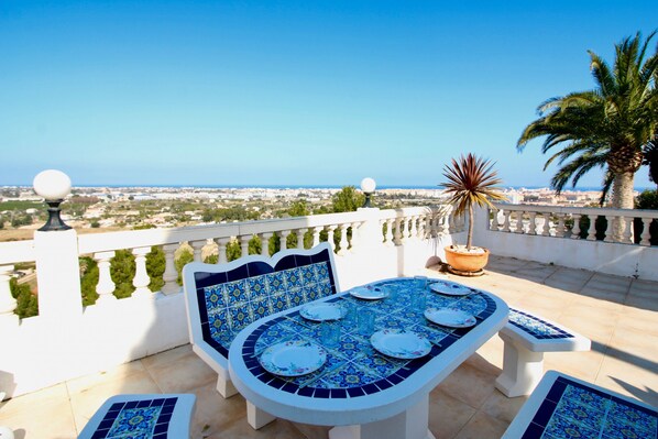 A terrace with a table set for dining, a chair, and a potted plant. - Villa with sea views, air conditioning and Marquesa CaMar pool 4 people (Denia)
