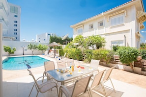 A poolside area with a table and chairs, a satellite dish, and a building with a tiled roof. - Jason 8  Villa (Paralimni)