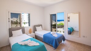 Une chambre d’hôtel avec deux lits, un balcon avec vue et un grand miroir.