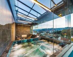 Un spa moderne doté d’un jacuzzi en verre, d’un espace détente et d’une vue sur la ville.