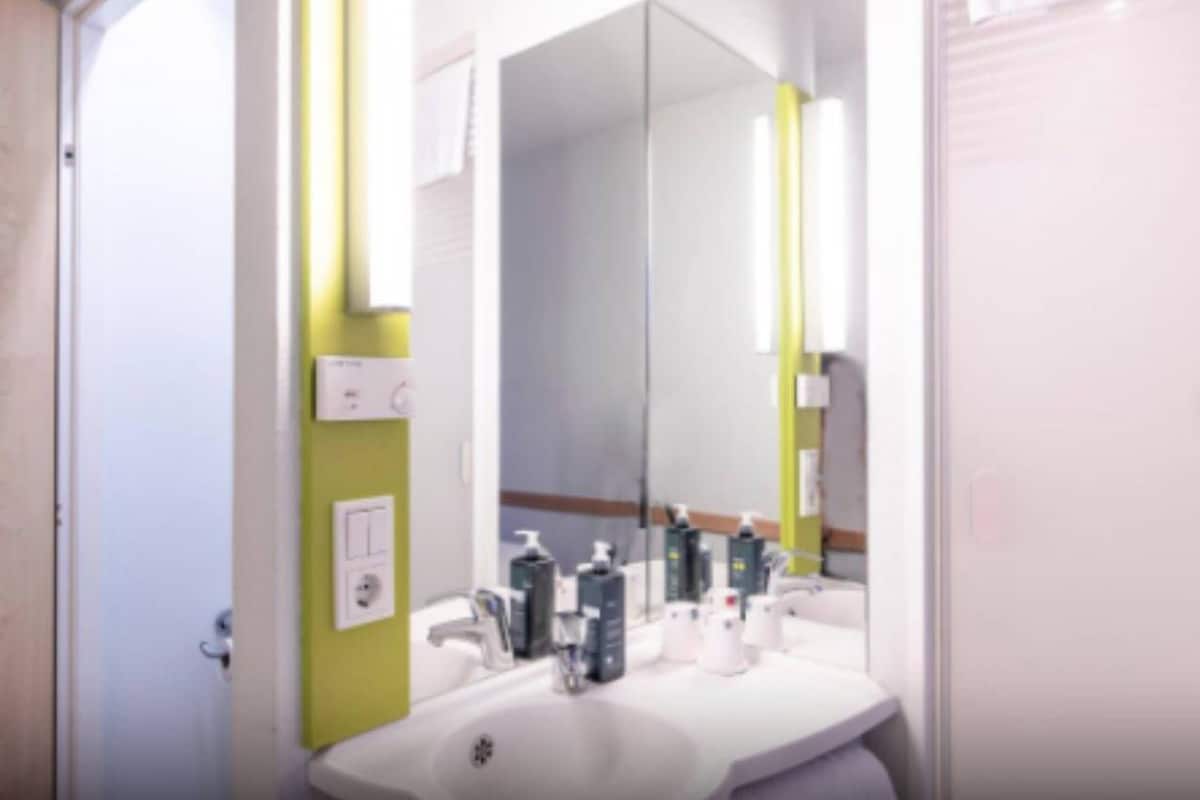 Une salle de bain avec un lavabo blanc, un miroir et des articles de toilette posés sur le comptoir.