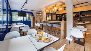Un restaurante moderno con área de bar, mesas y sillas blancas.
