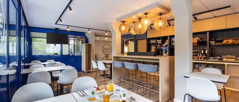 A modern restaurant with a bar area, white tables, and chairs.