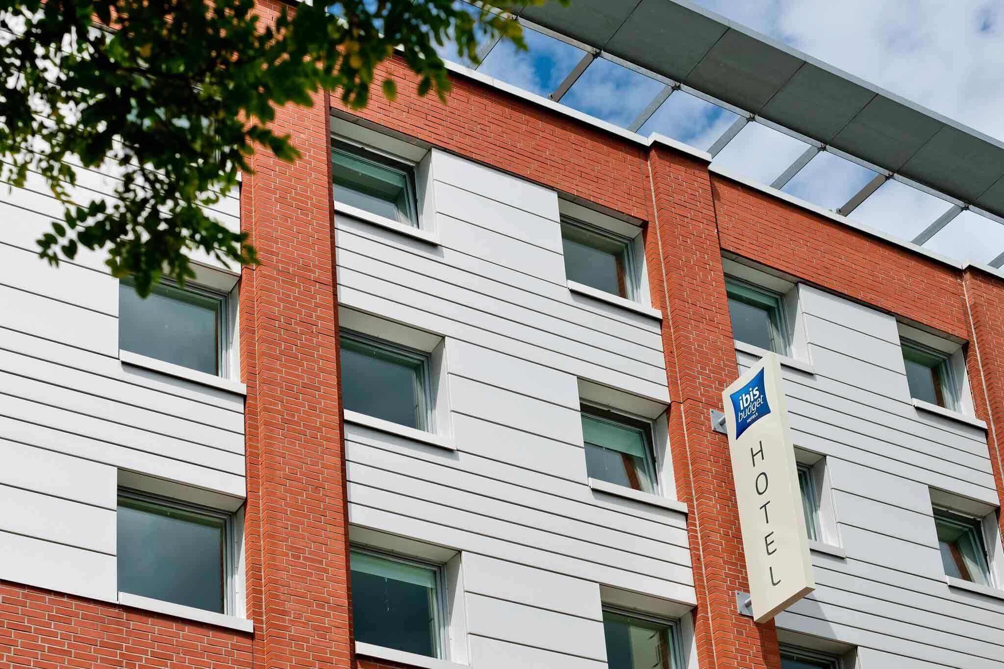 A hotel building with a modern architectural design, featuring horizontal white siding and red brick walls.