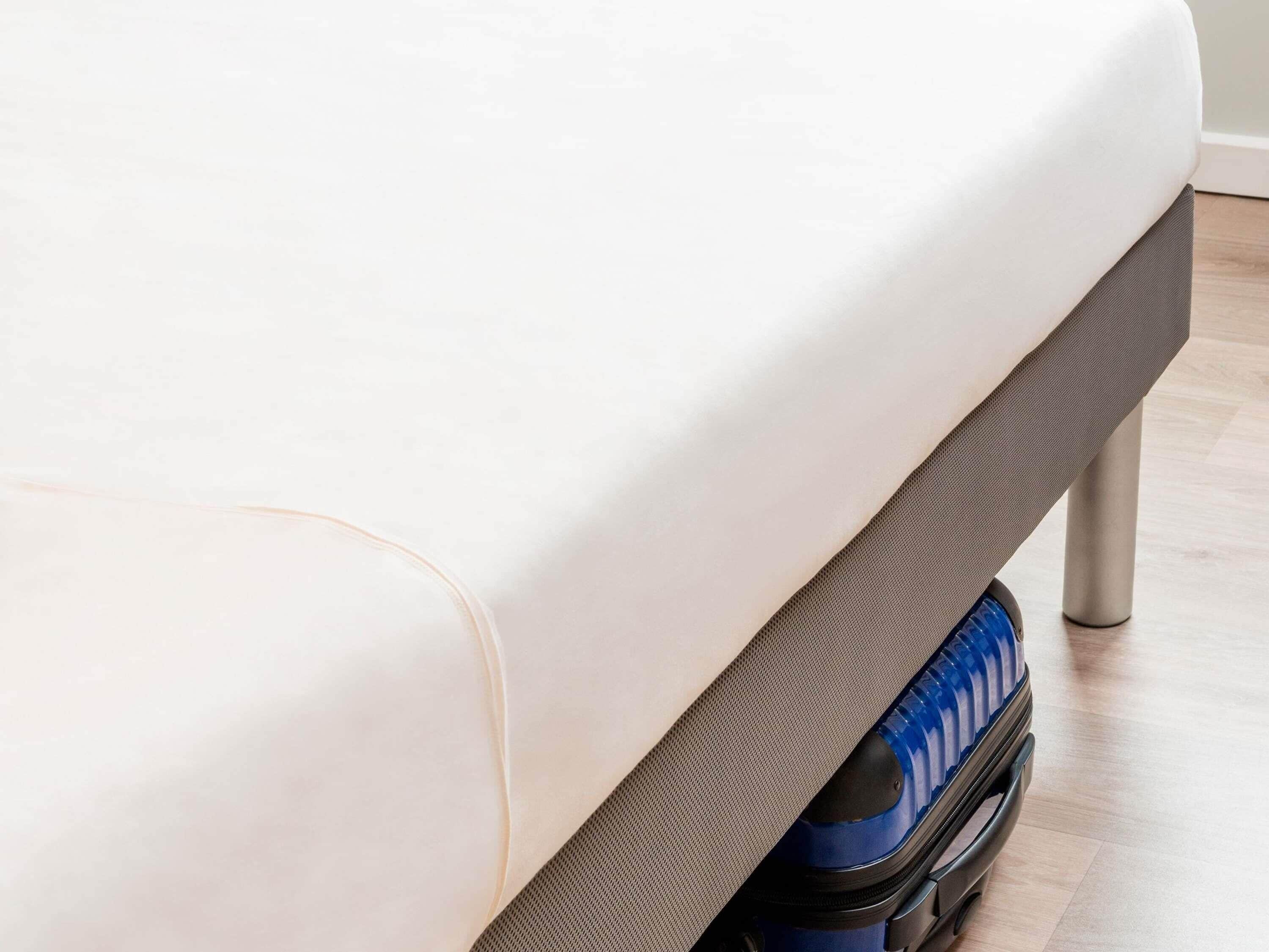 Een bed met een witte matras en een grijze basis.