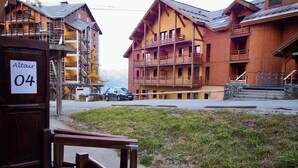 A wooden building with balconies and a car parked in front. - Risoul - Apartment 04 - Fully equipped - WIFI - 30m² - Foot of ski area (Risoul 1850)