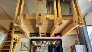 A room with exposed wooden beams, a window with curtains, and a refrigerator with a no-smoking sign. - Risoul - Apartment 04 - Fully equipped - WIFI - 30m² - Foot of ski area (Risoul 1850)