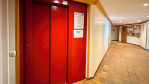Um corredor com uma porta vermelha, teto de madeira e chão de azulejos.