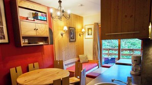 A compact kitchen with a wooden dining table, a built-in sink, and a coffee maker. - Risoul - Apart 202 - Pool/Sauna - WIFI - Fully equipped - Foot of slopes (Risoul)