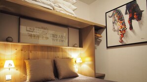 Une chambre à coucher avec une tête de lit en bois, deux lampes de chevet, une citation encadrée accrochée au mur et un tableau abstrait aux couleurs vives.