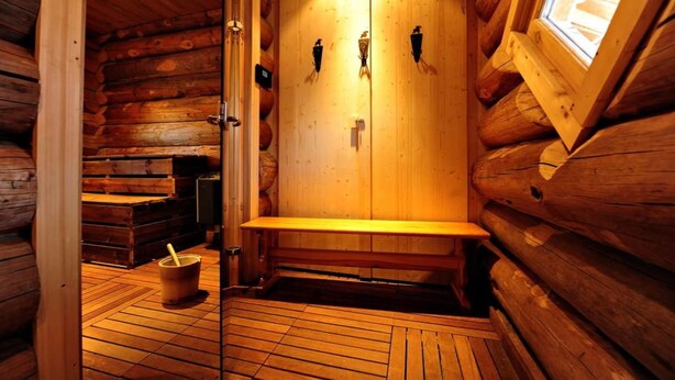 Un sauna en bois avec des bancs et un seau.