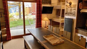 Une petite pièce comprenant un lit superposé, une table avec un plateau, un téléviseur et une cheminée.