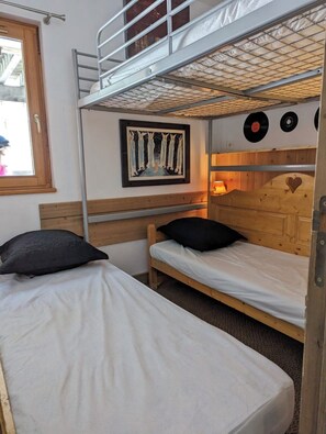 Une chambre avec un lit superposé, une tête de lit en bois, une œuvre d’art encadrée et un lecteur de disques fixé au mur.
