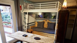 A bunk bed room with a wooden table, two chairs, a small stool, and a cabinet. - Risoul - Studio 02 - Fully equipped - WIFI - 30m² - Foot of ski area (Risoul 1850)