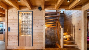 Un intérieur en bois, agrémenté d’un meuble de rangement à façade en verre, d’un escalier en pierre et d’un plancher en bois.