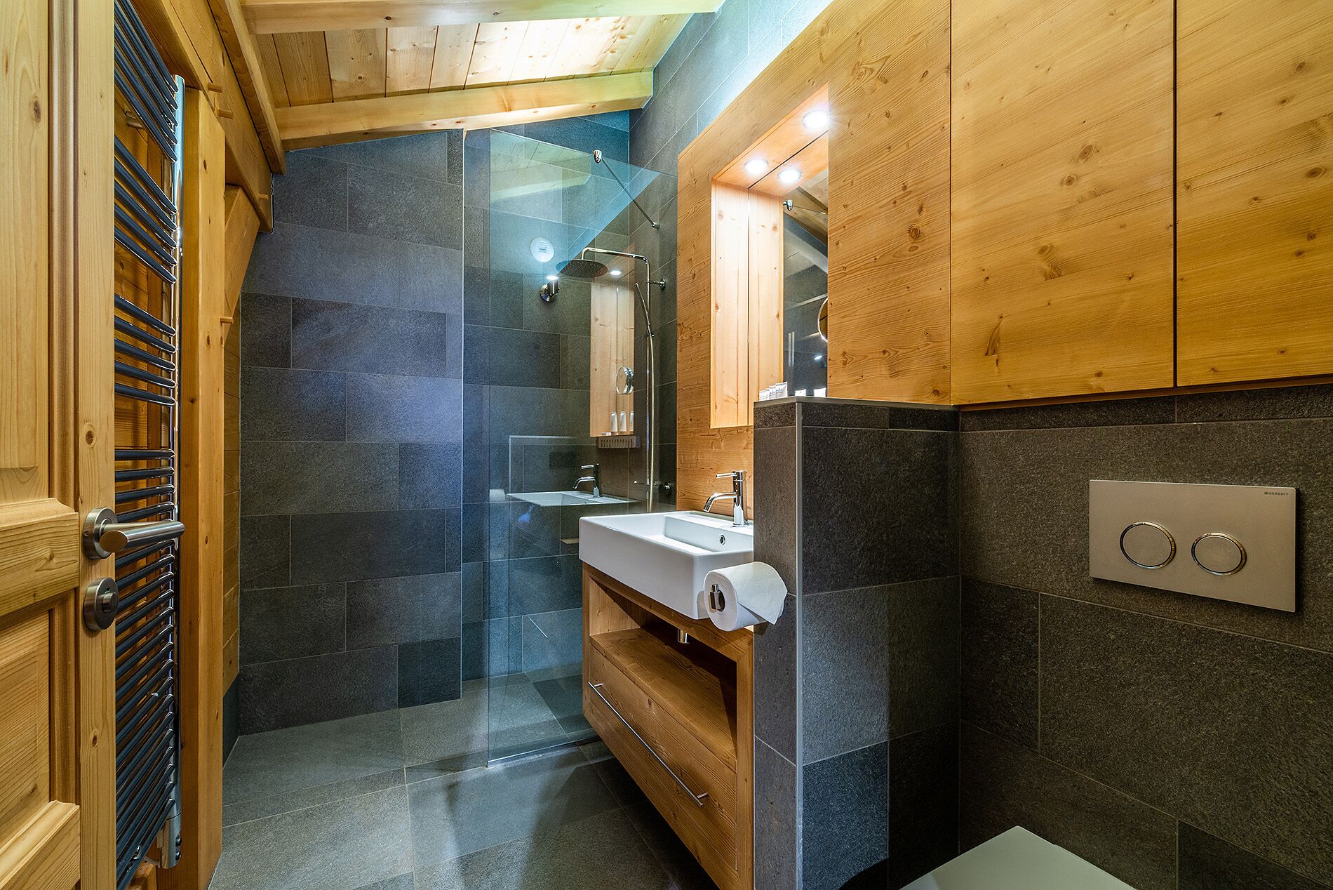 Une salle de bain moderne avec une douche à parois de verre, des meubles en bois et un lavabo intégré.