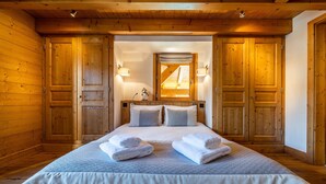 Une chambre à coucher aux murs lambrissés, avec un lit, deux lampes de chevet et un miroir au-dessus du lit.