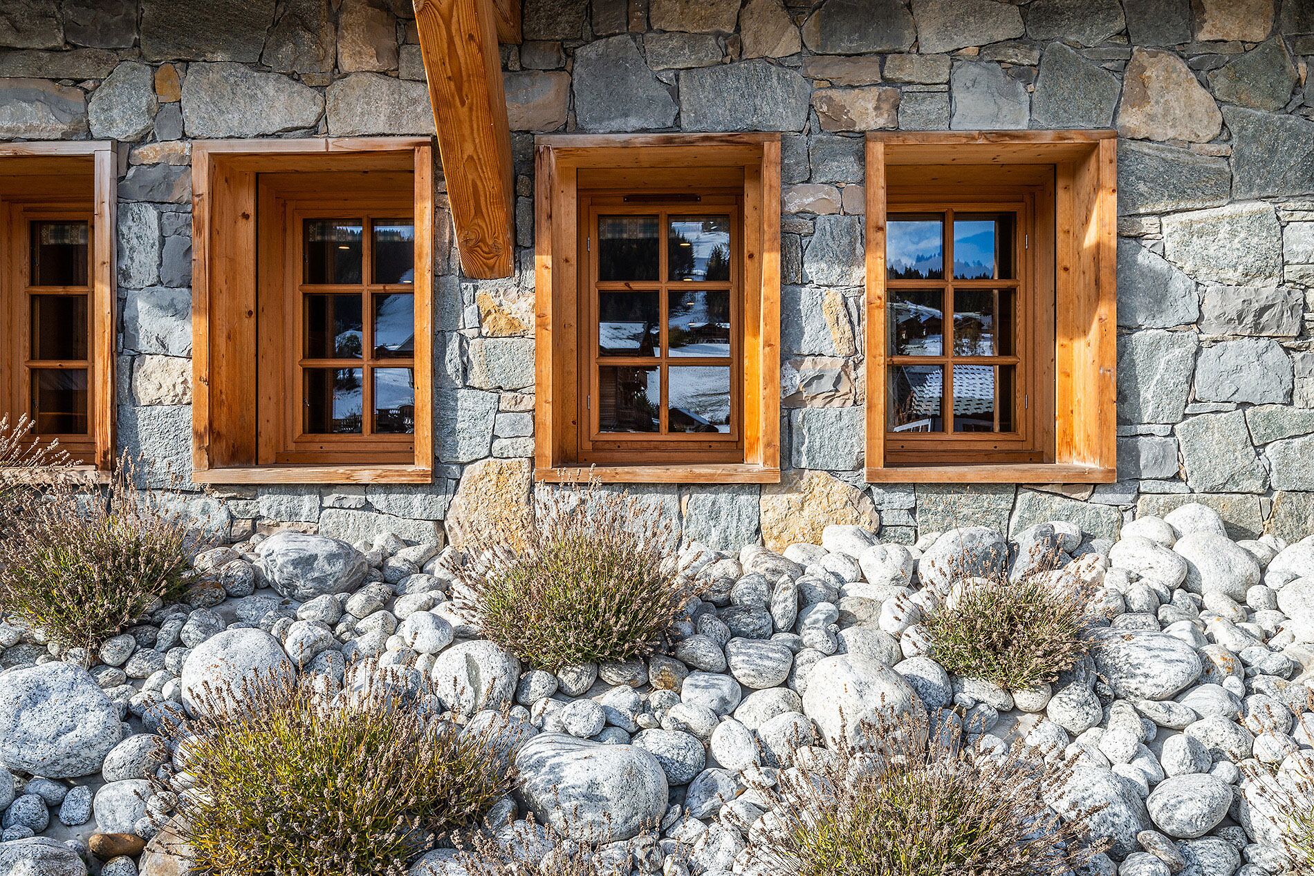 Ein Steinhaus mit drei Fenstern, die hölzern eingefasst sind.