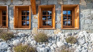 Ein Steinhaus mit drei Fenstern, die hölzern eingefasst sind.