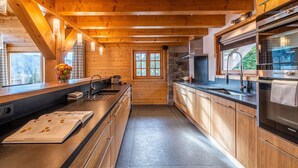Une cuisine moderne avec des poutres en bois, un mur d’accent en pierre et un réfrigérateur Siemens.