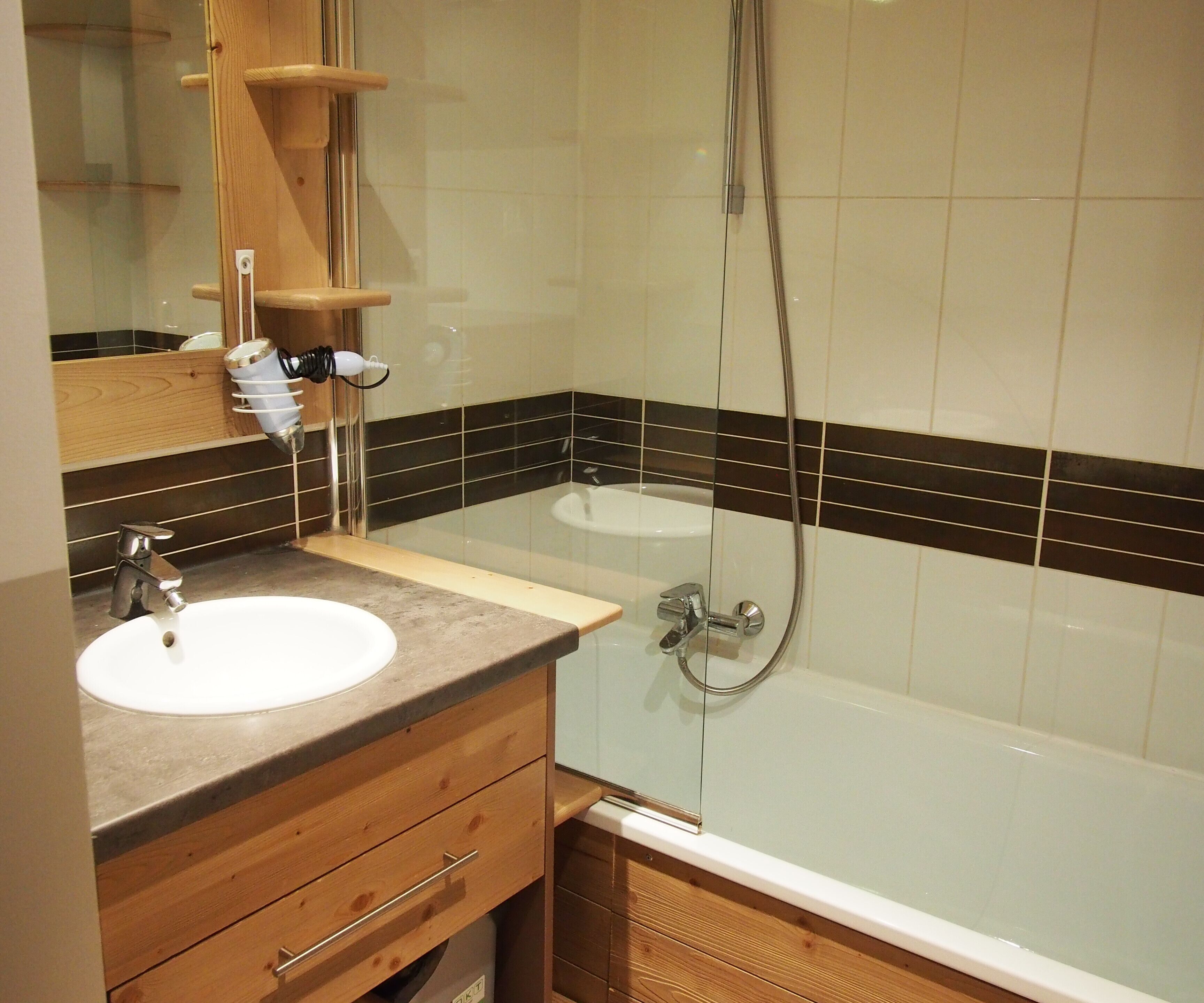 A bathroom with a wooden vanity, a sink, a mirror, a shower, and a bathtub.