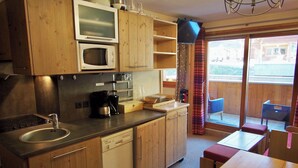 A compact kitchen with wooden cabinets, a microwave, a coffee maker, and a dishwasher. - Risoul - Apart 410 - Pool/Sauna - WIFI - Fully equipped - Foot of slopes (Risoul)