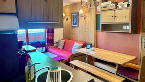 A cozy cabin-style room with a wooden interior, a red sofa, a wooden table, and a bench. - Risoul - Apart 410 - Pool/Sauna - WIFI - Fully equipped - Foot of slopes (Risoul)