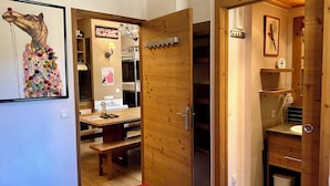 Une pièce avec une porte en bois, un banc, une moquette rouge et un tableau représentant un chameau accroché au mur.