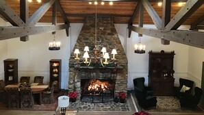 Un interior acogedor con chimenea de piedra, vigas de madera y un candelabro.