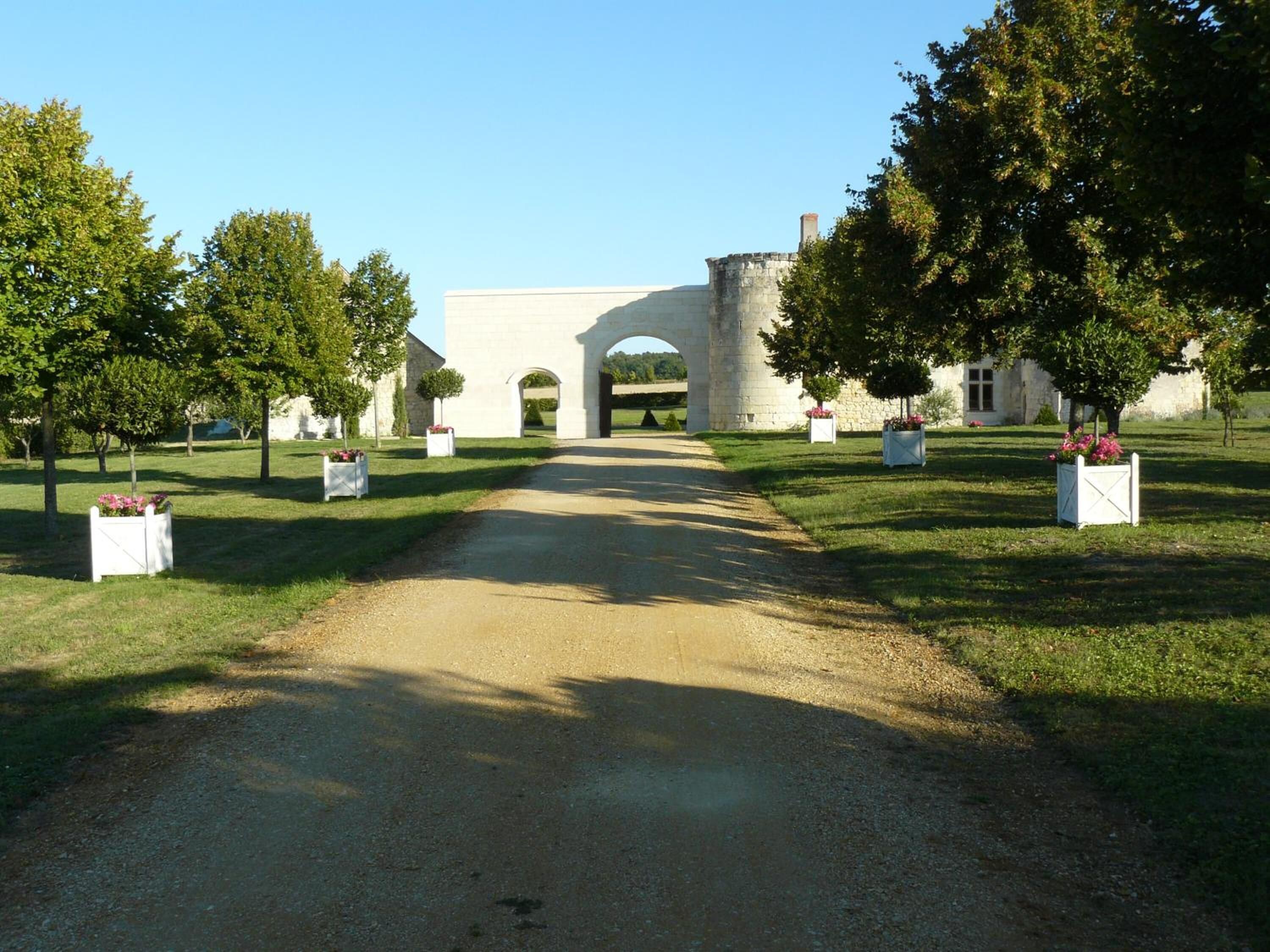 A paved pathway leading to a stone archway with a building in the background.