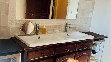 Bany amb un lavabo doble, mobles de fusta i un mirall gran.