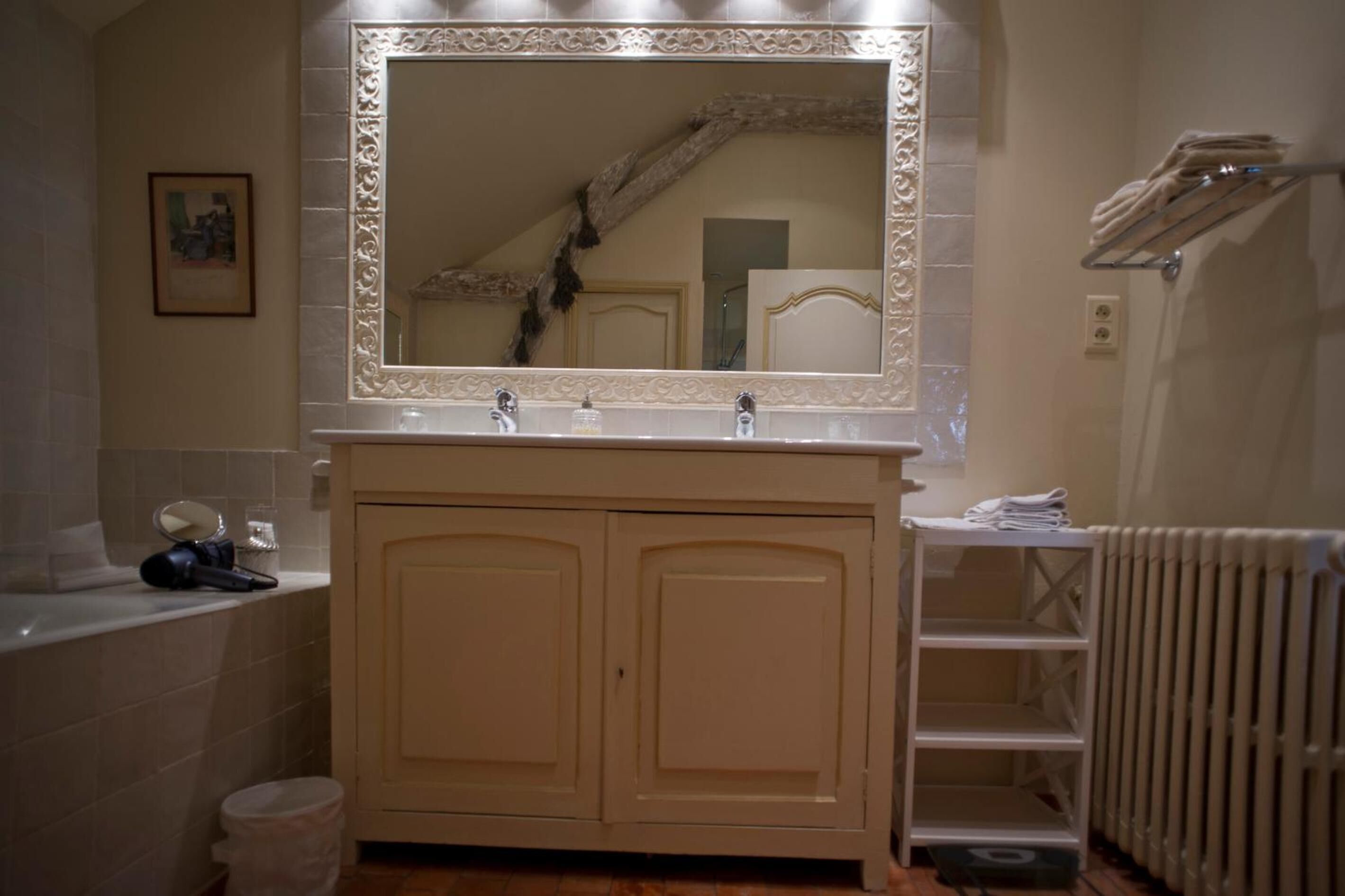 A bathroom with a large mirror, two sinks, a towel rack, and a radiator.